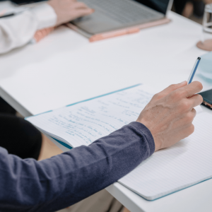 mão a segurar uma caneta em cima de um caderno